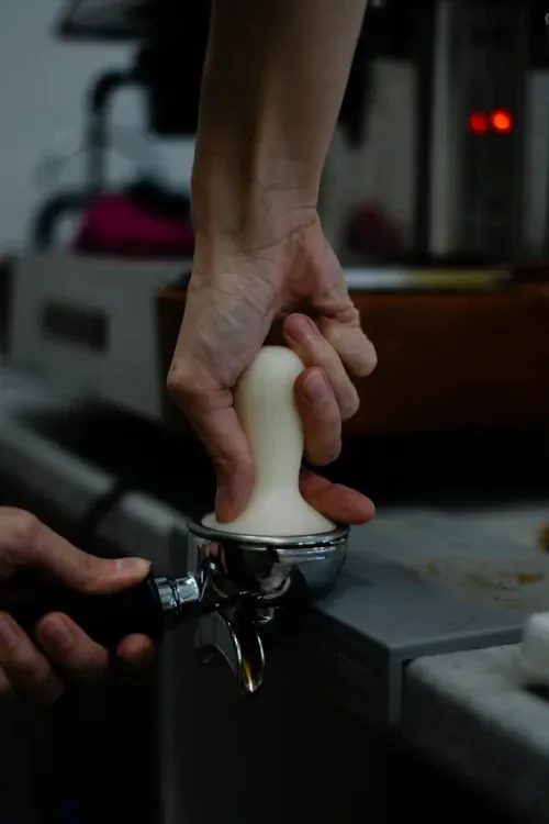 A barista tamping coffee grounds in a portafilter