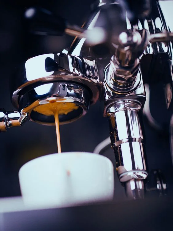 Espresso pouring from a portafilter into a white cup